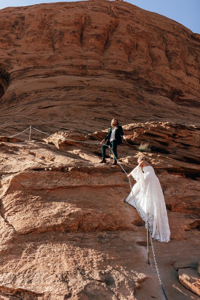 adventurous elopement couple hiking the red rock cliffs in moab during their skydiving wedding day