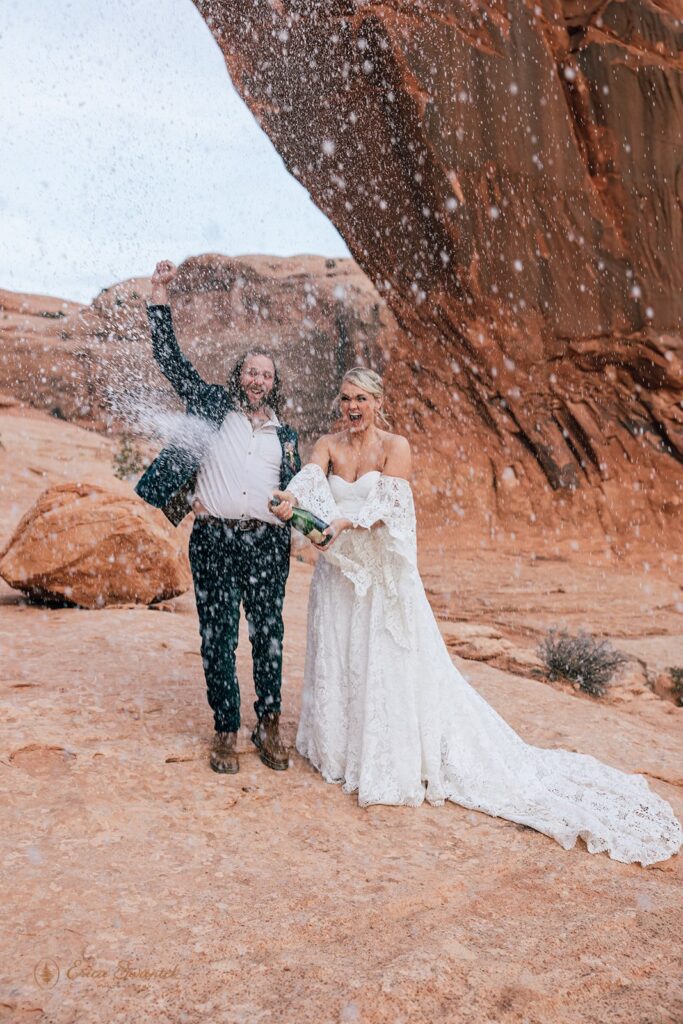 bride and groom popping champagne during their moab desert elopement