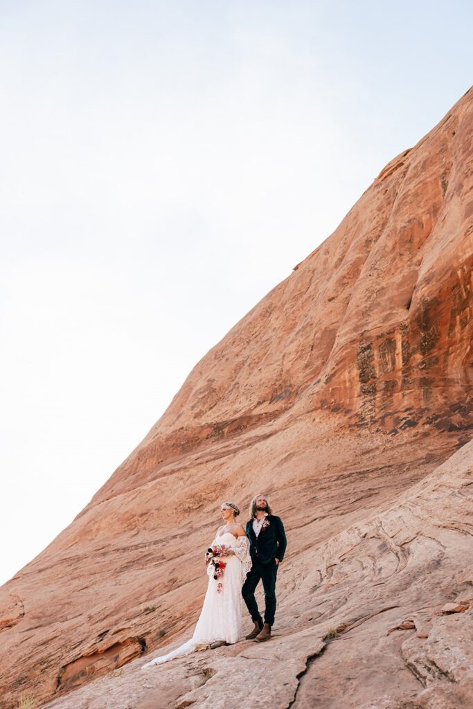 adventurous elopement couple hiking the red rock cliffs in moab during their skydiving wedding day