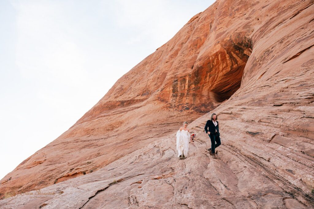 elopement couple hiking the corona arch for their moab adventure elopement