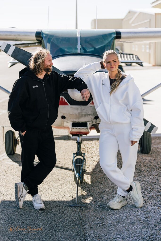 elopement couple posing in front of a small plane ahead of their skydiving wedding in moab, utah