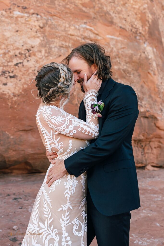 playful elopement couple kissing in front of a red rock wall in moab desert