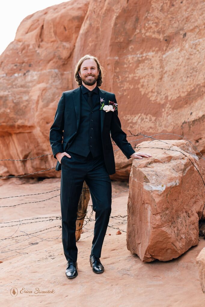 groom in front of red rock formations during western elopement in moab