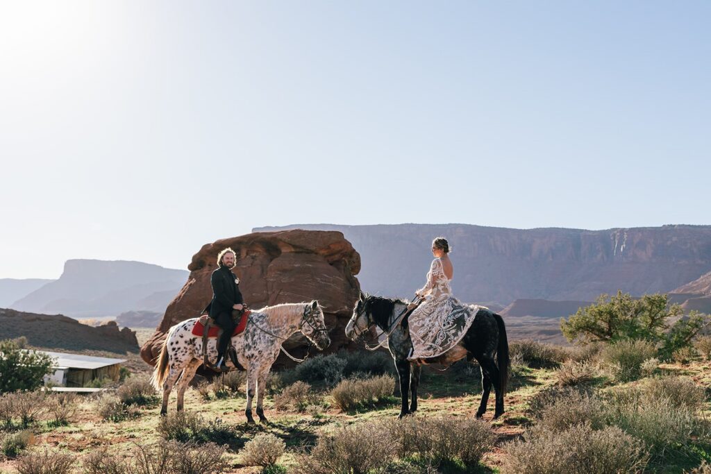 bride and groom horseback riding during their western elopement in moab