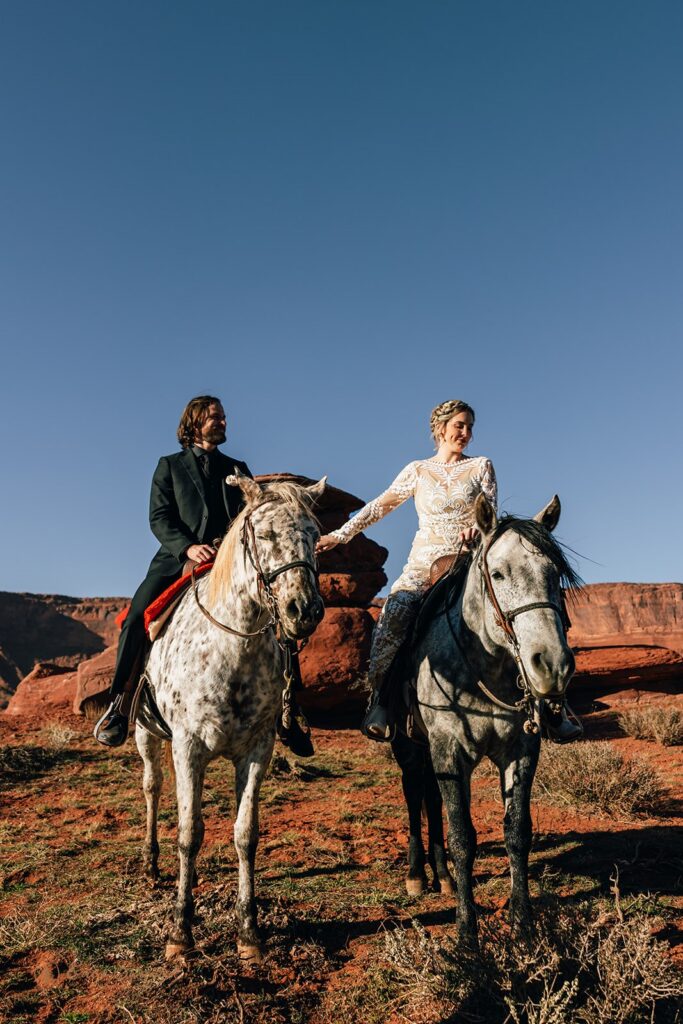 bride and groom horseback riding during their western elopement in moab