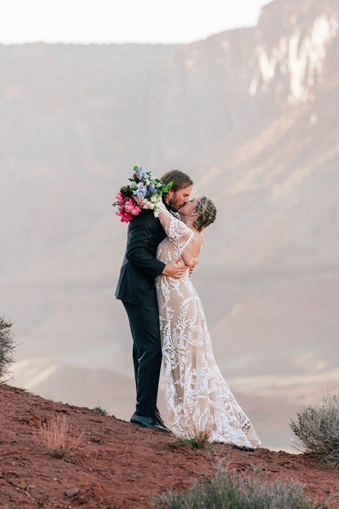 elopement couple kissing during their western elopement in moab