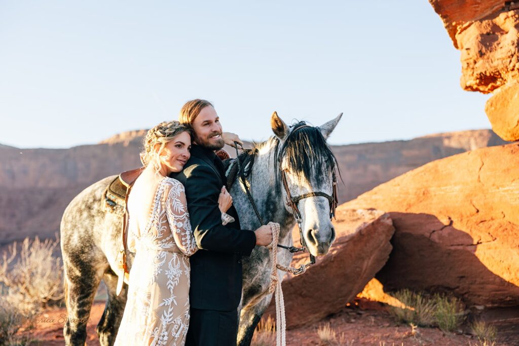 bride and groom posing with their horse during their western elopement in moab