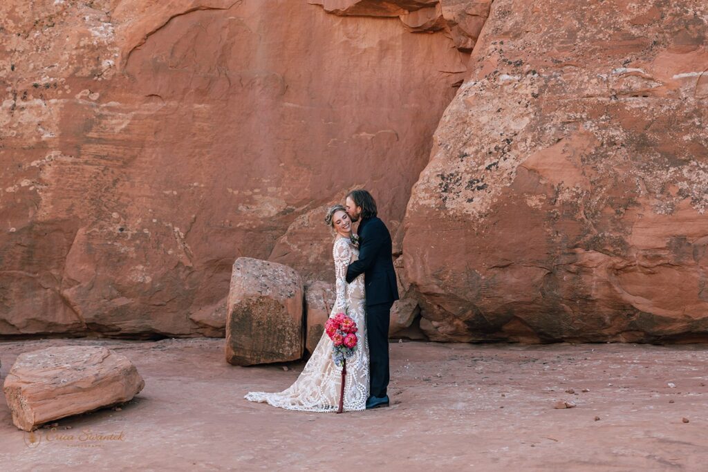 playful elopement couple in front of a red rock wall in moab desert