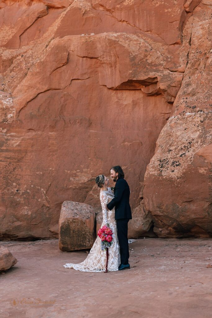 playful elopement couple kissing in front of a red rock wall in moab desert