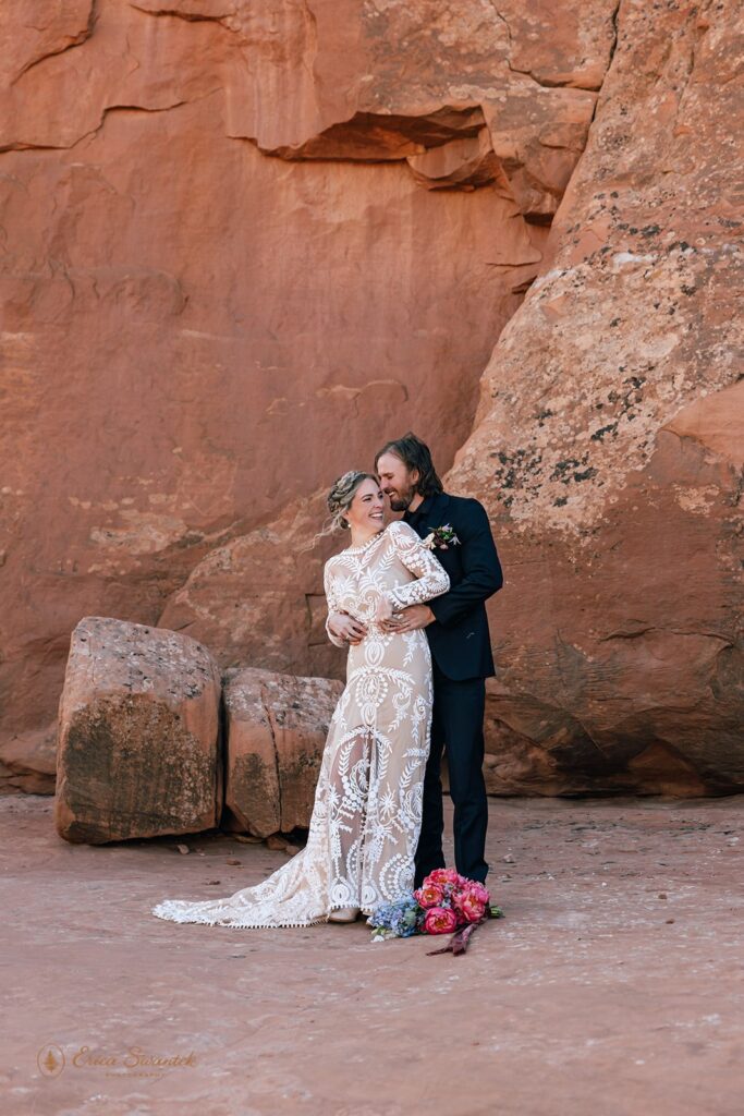 playful elopement couple in front of a red rock wall in moab desert