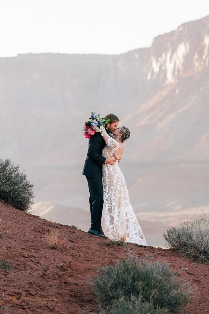 elopement couple kissing surrounded by desert landscapes as they elope in Moab