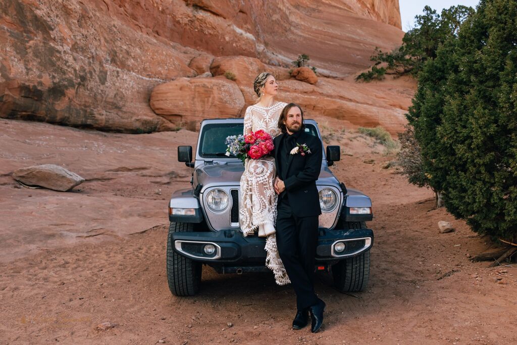 bride and groom posing in front of a jeep
