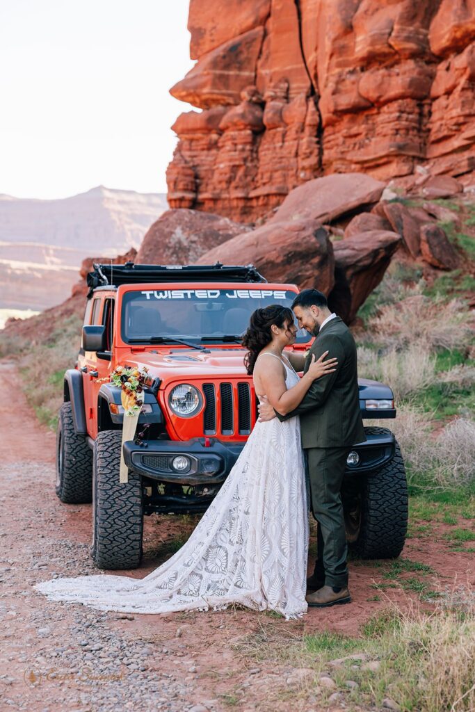 adventurous elopement couple hugging in front of a jeep during their moab elopement
