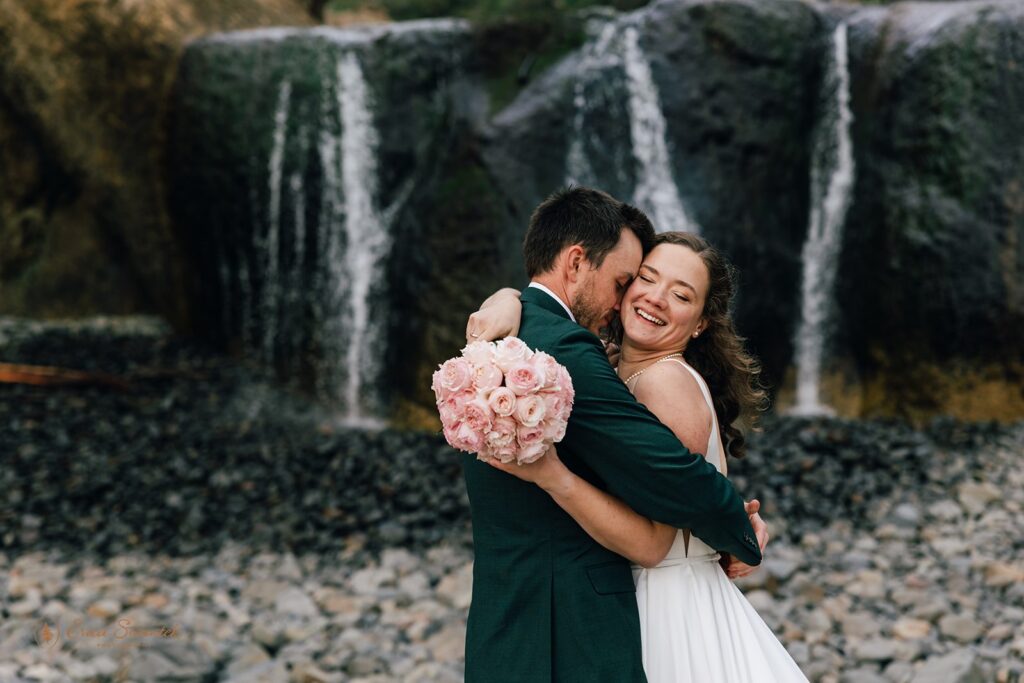 fun bride and groom moments during their pnw elopement in front of a small waterfall