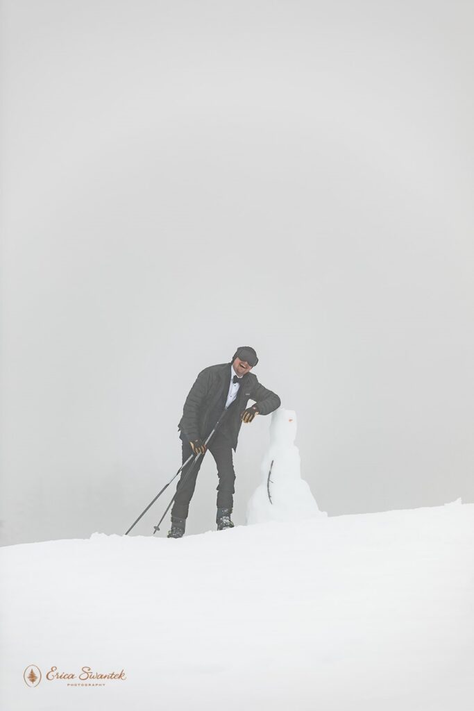happy groom with a snowman during a winter elopement in oregon