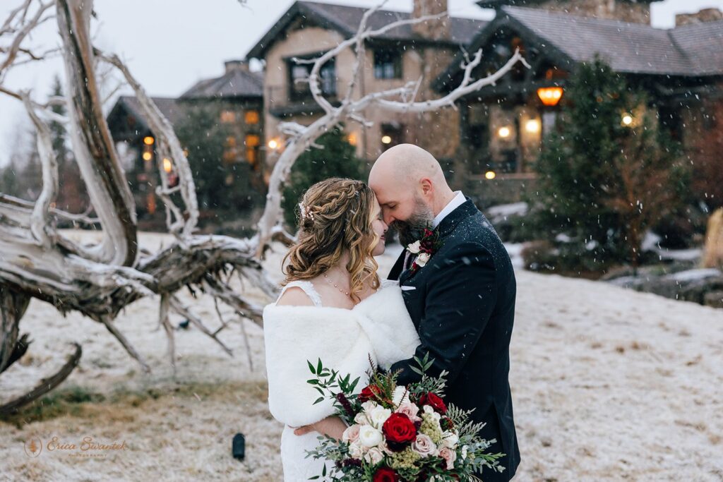 elopement couple snuggling as snow is falling on them