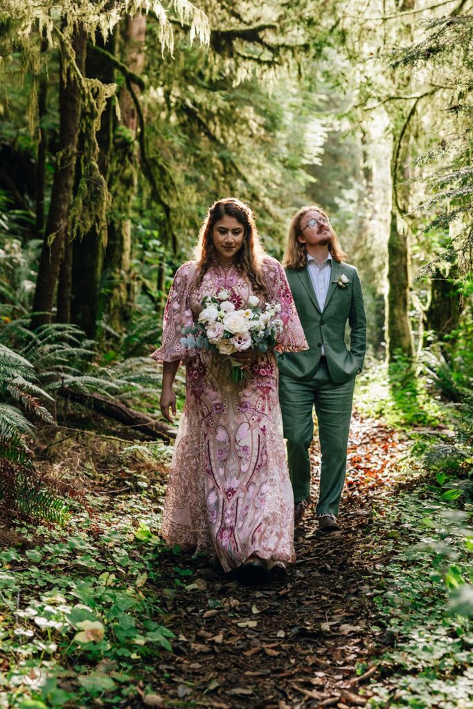 bride and groom walking through a lush forest