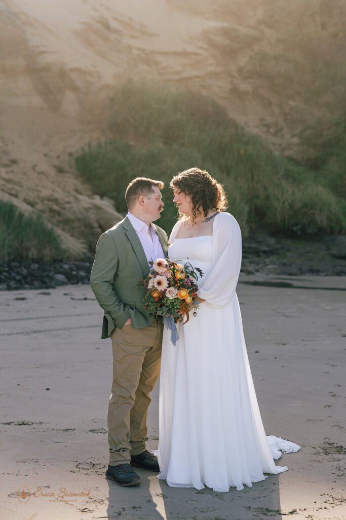elopement couple gazing at each other along oregon coast