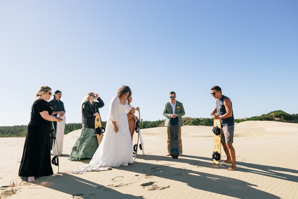 bride and groom and friends sandboarding during an adventure elopement day in the pnw
