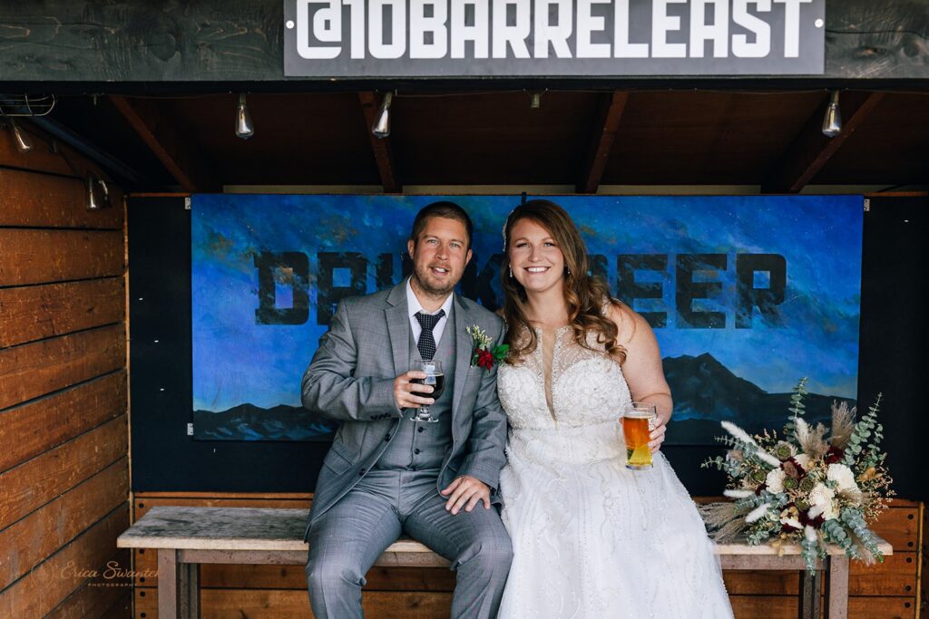 elopement couple smiling and holding beers at an oregon brewery