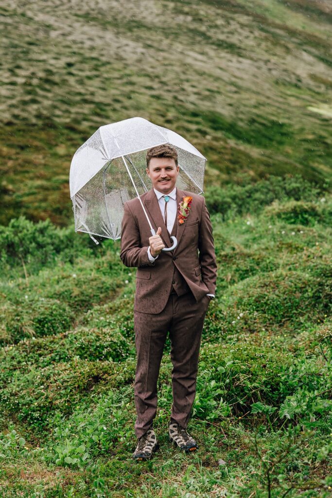 adventurous groom with a clear umbrella during a rainy elopement day in Alaska