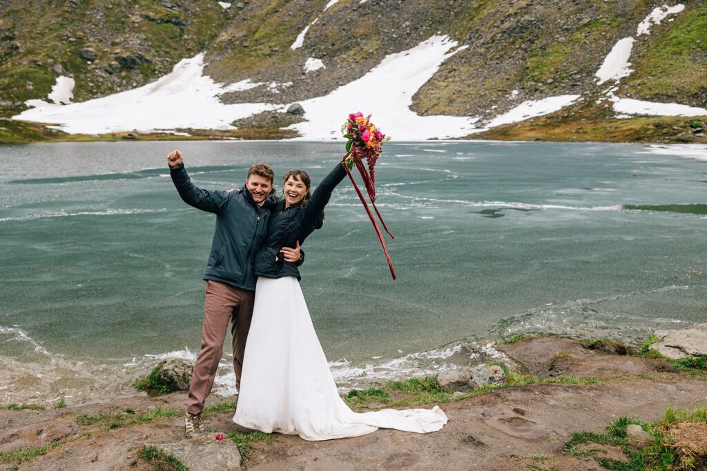 joyful elopement couple next to a frozen lake during their alaska elopement